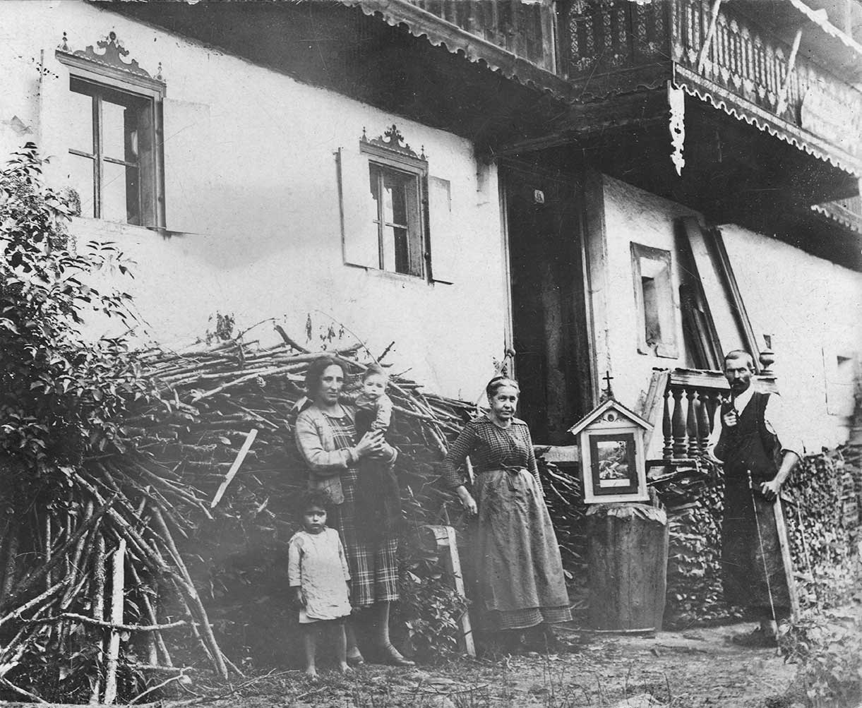 Historische Aufnahme mit Vorfahren der Familie Bacher vor dem Bauernhaus, links im Bild ein Hollerbuchsen